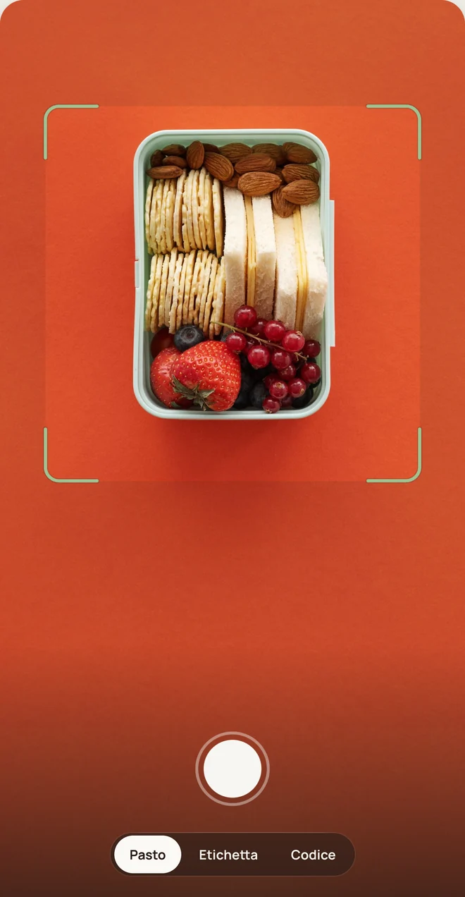 La fotocamera puntata su un portapranzo con panini, cracker, mandorle e frutta.